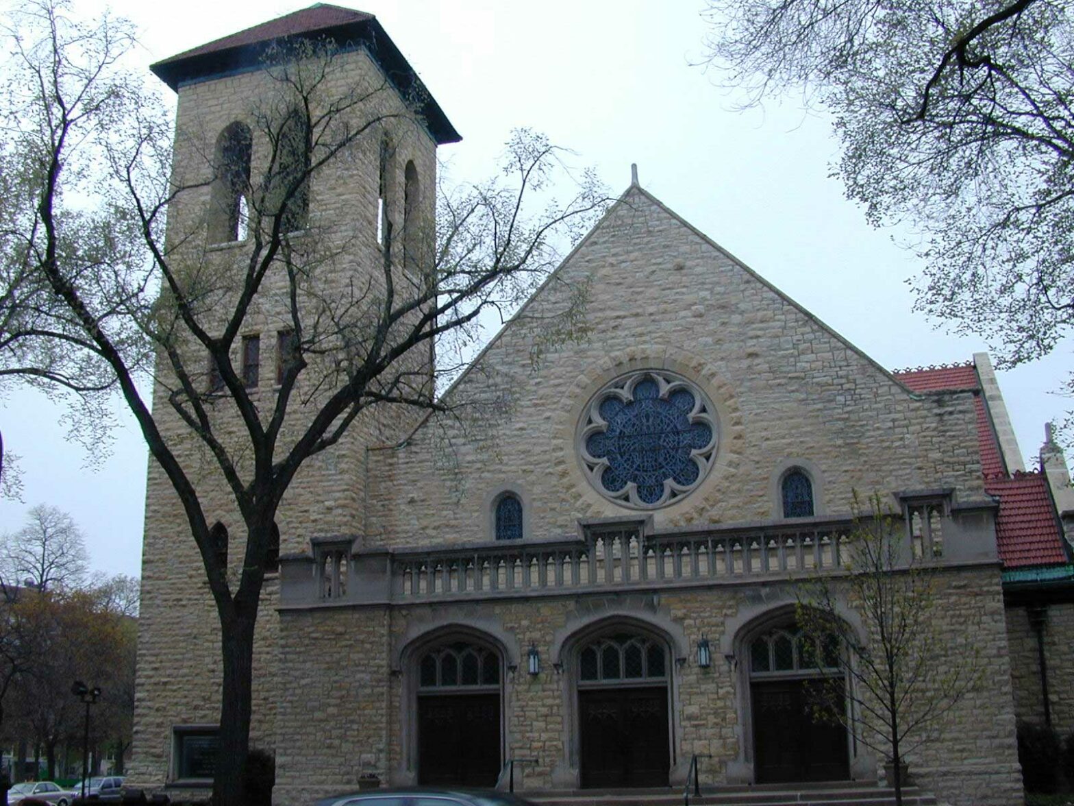 The exterior of First Presbyterian Church shows a brick and stone exterior with a bell tower hidden behind a winter tree.