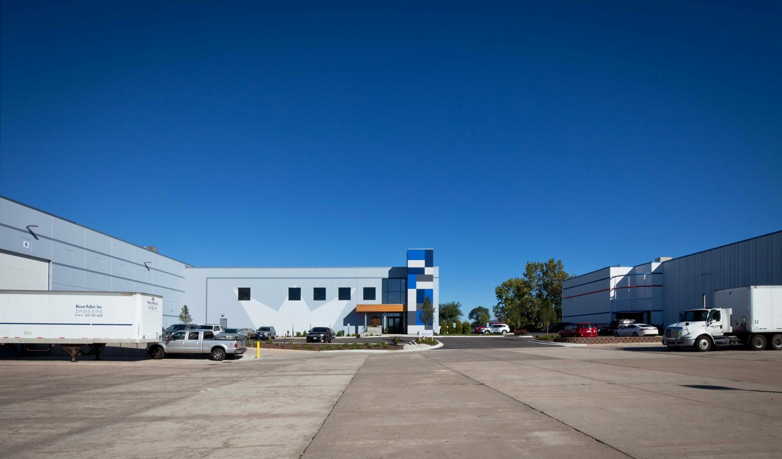 The back area of Royal Die and Stamping's headquarters shows a white building with shipping docks and trucks.