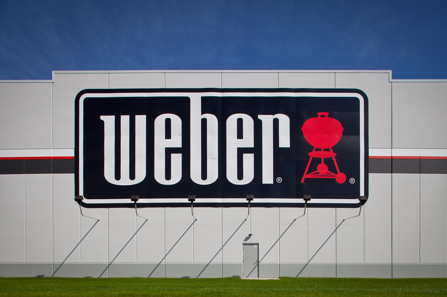 A close-up of a sign on the side of a building. The sign says, "Weber," and has a picture of a grill to the right of the text.