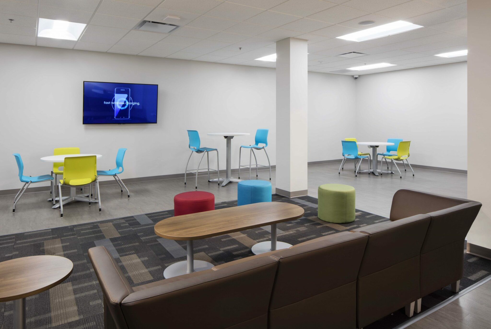 BCI Acrylic has a modern employee lounge with colorful plastic chairs, a brown couch and tables of varying heights.