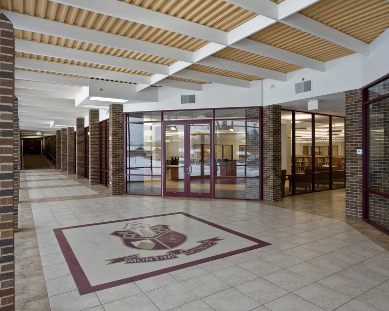 Montini Catholic High School’s front entrance has red brick walls and the school’s red crest on the tiled floor, creating a warm and professional impression built by Keeley Construction.