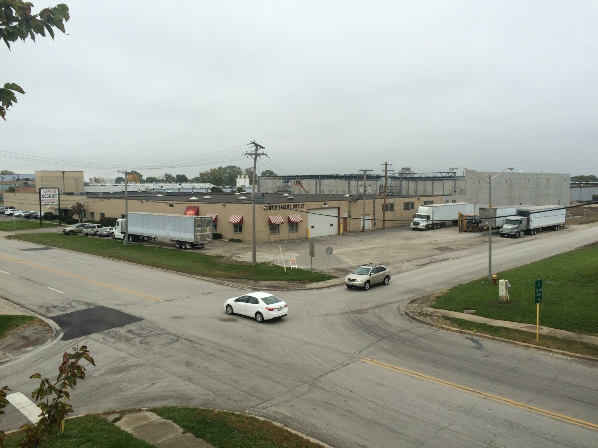 The “before” image of the Pure’s Food facility shows a run-down industrial building with red and white striped awning over the few windows, concrete wall construction on the back of the facility, and trucks parked in the parking lot while cars use the street in front.