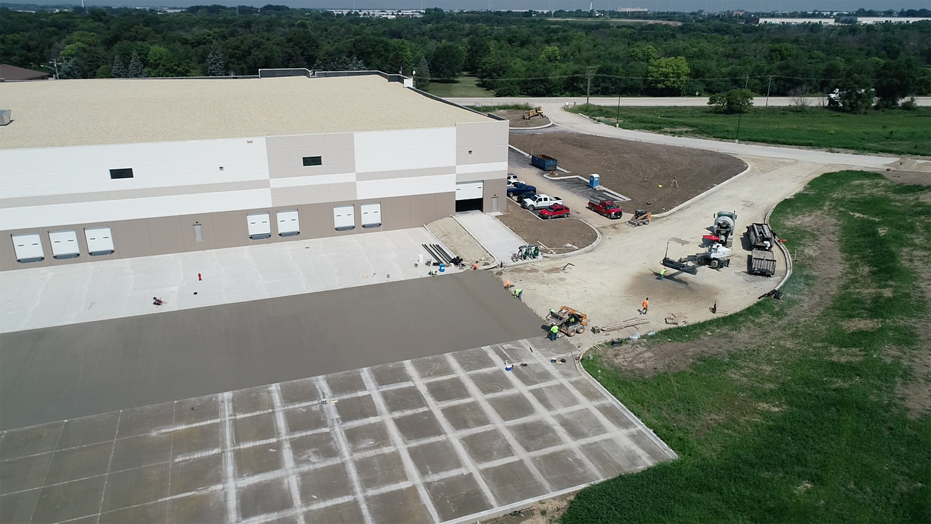 A white industrial building with driveways and a field with a white grid.