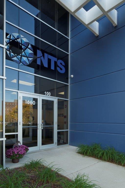 The exterior of the National Technical Systems building’s entry way. The glass door has the number “1660” and the glass window above the door says “100.”