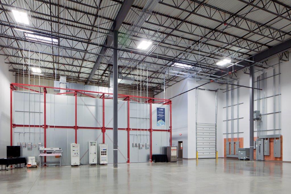 Metallic grids in red and grey line the walls and ceiling of the new National Technical Systems warehouse and equipment space, built by Keeley Construction, Inc.