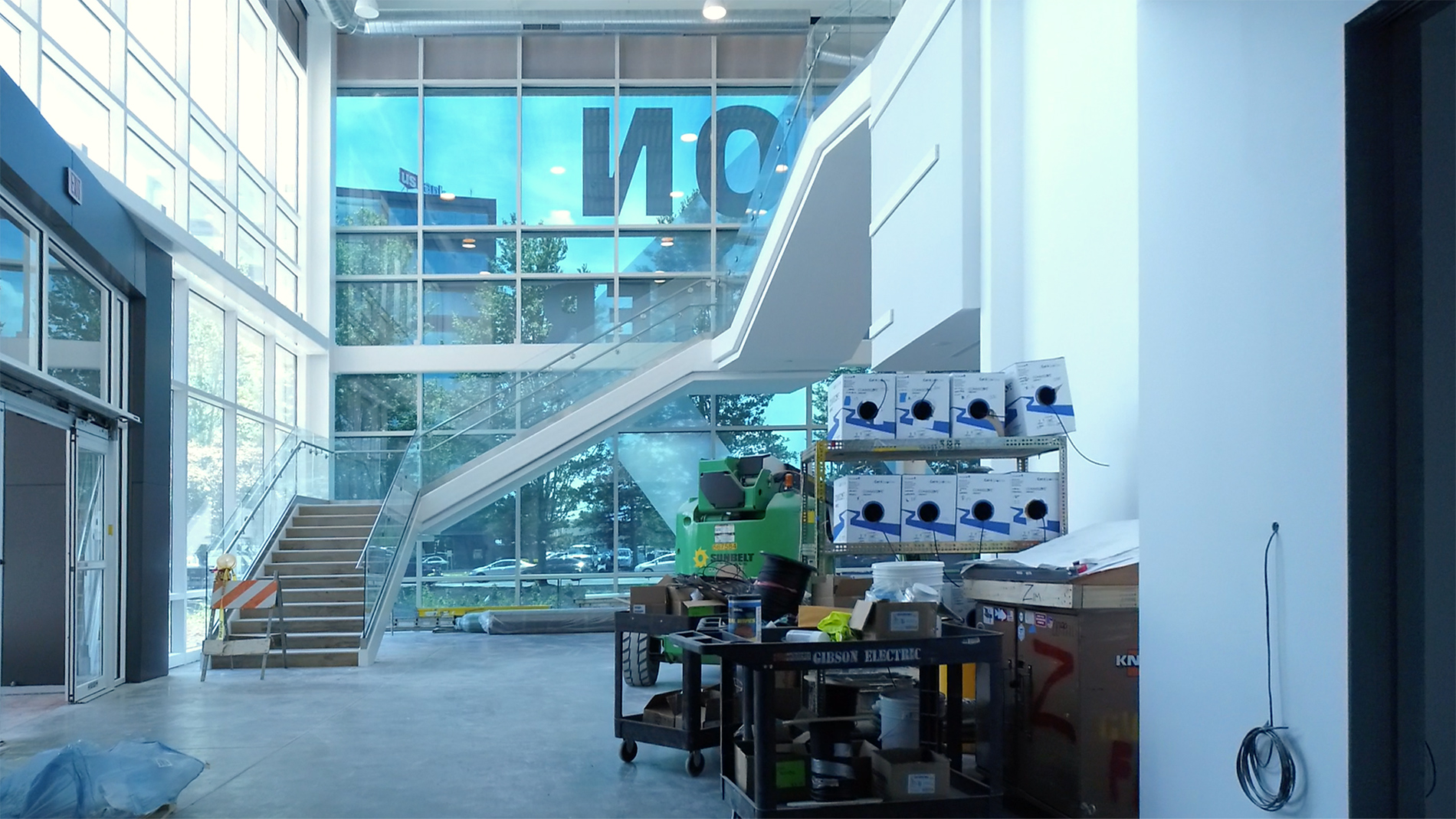 A staircase against a glass wall with supplies and renovation supplies in front.