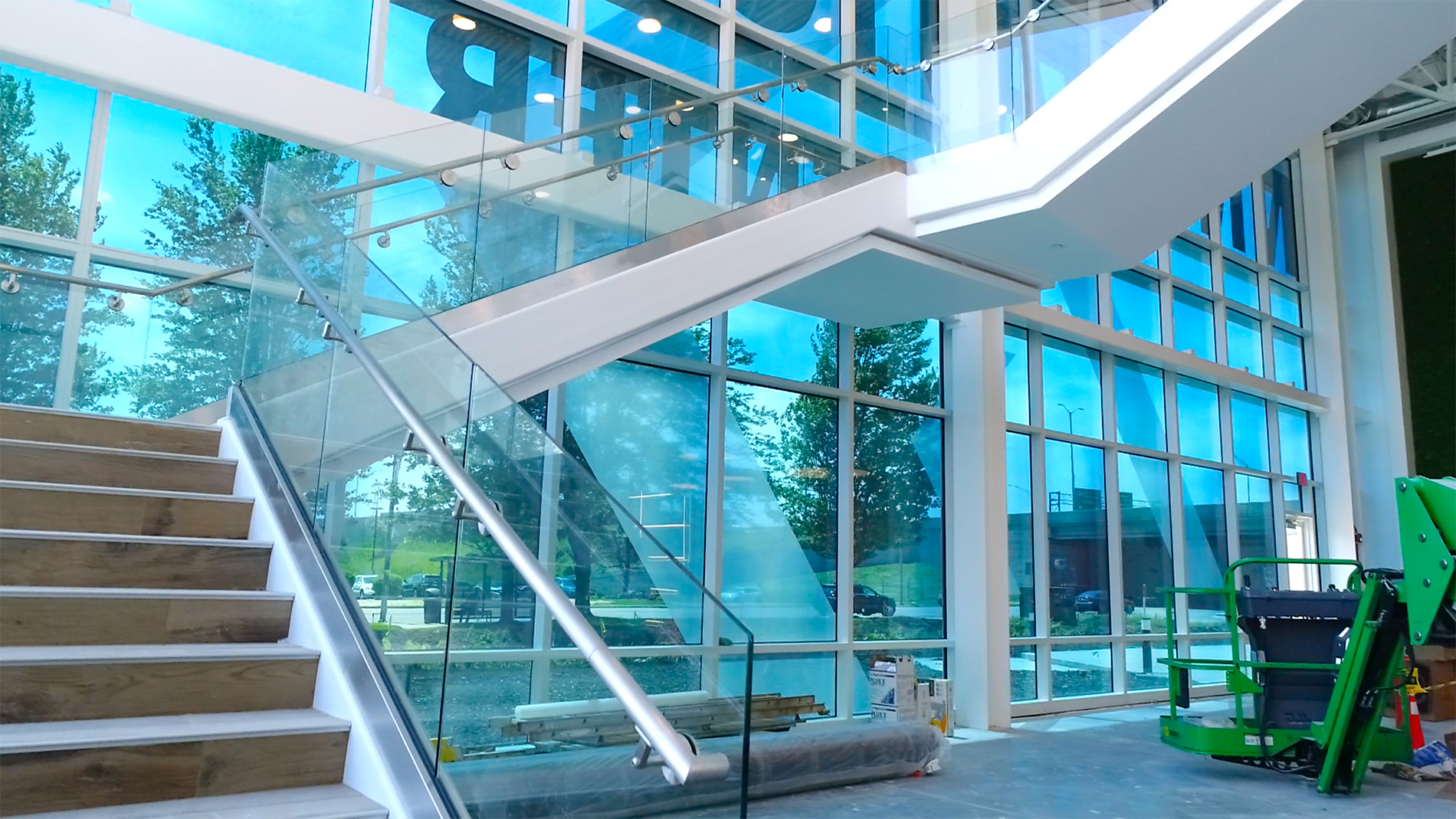 A modern stairway in front of a multiple-storied glass wall.