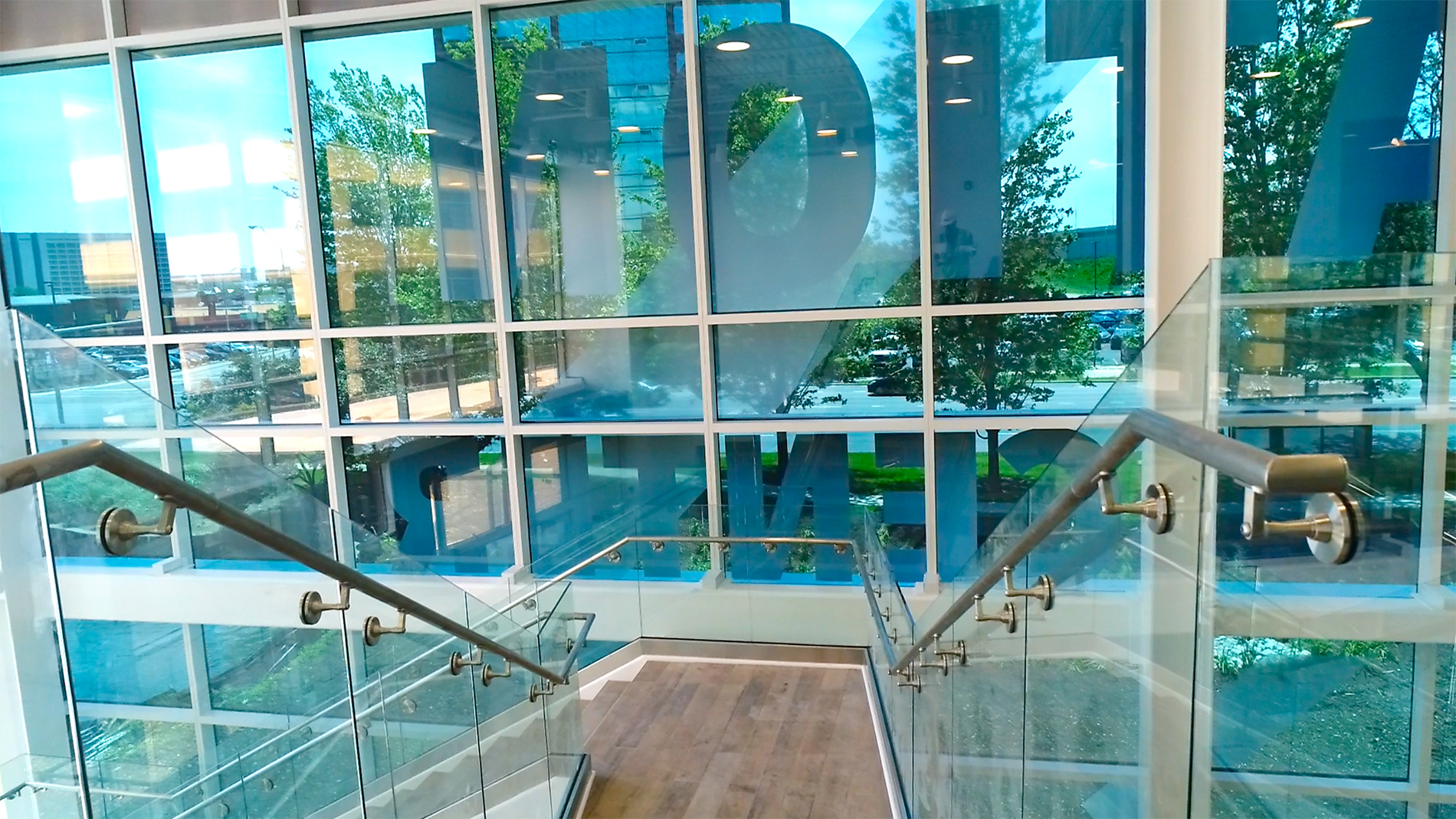 A glass wall with large letters in each window and a staircase in front.