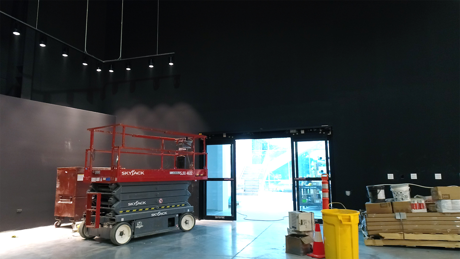 A big dark room with large doors behind a red platform with wheels.