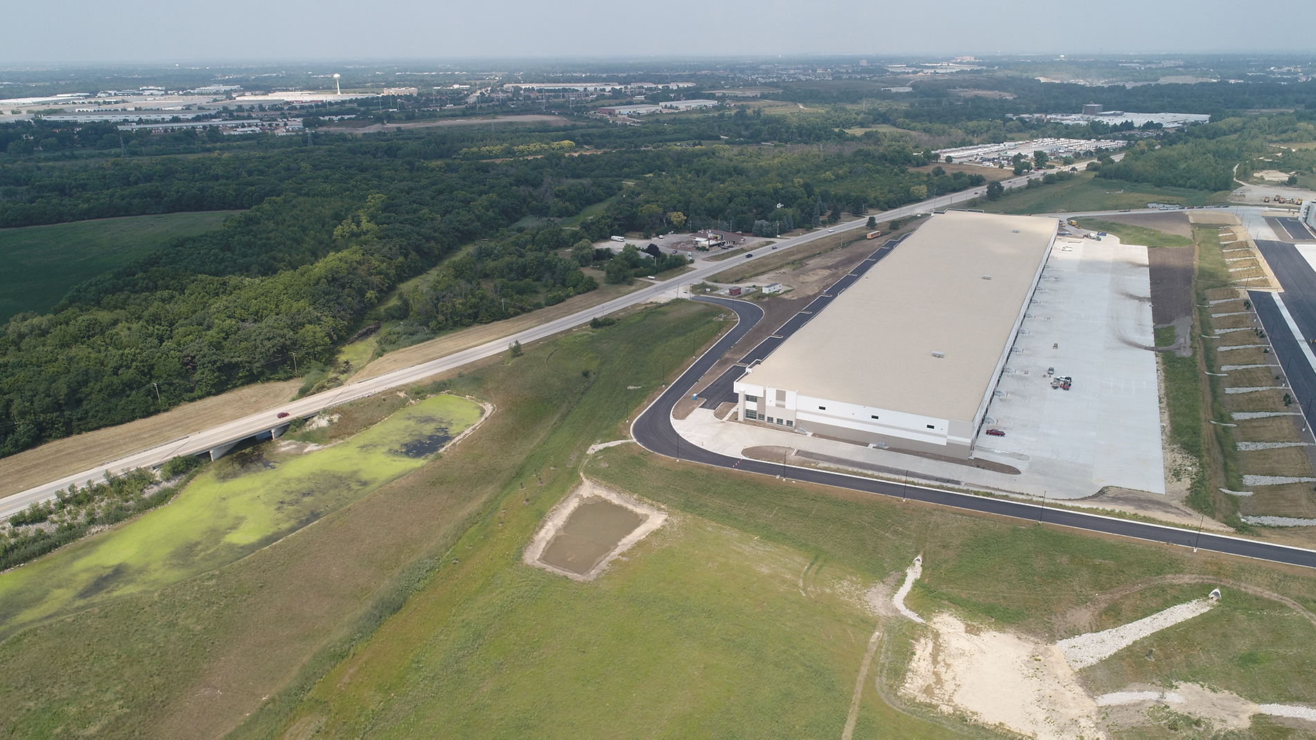 A faraway view of a white warehouse and the surrounding fields.