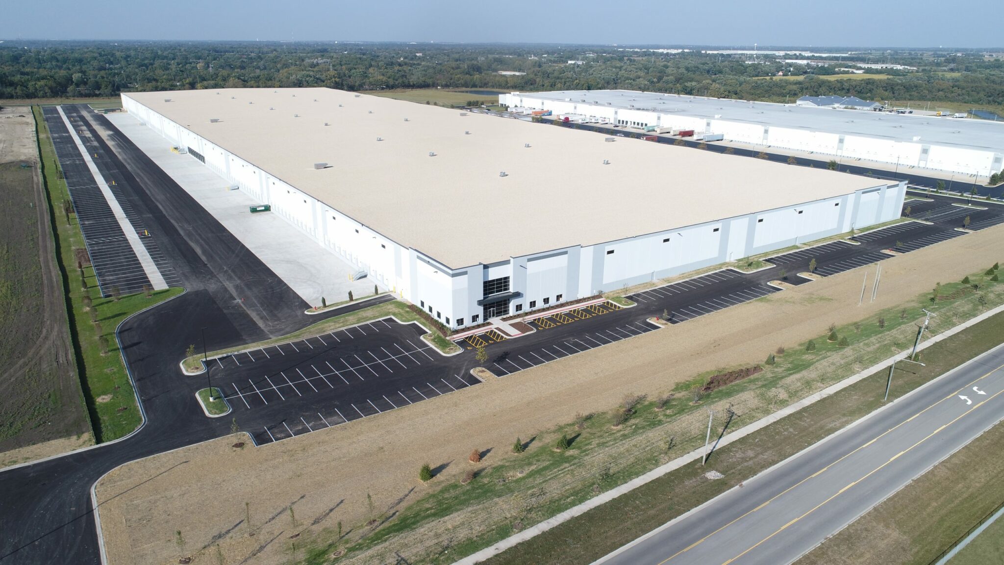 An aerial view of a new warehouse with a big lake in the distance.