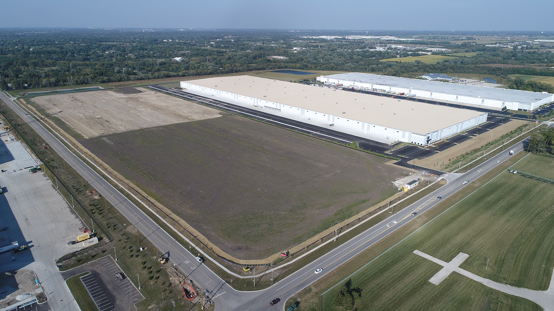 An aerial view of the new DHL warehouse and distribution center campus shows a large building, empty fields and a parking lot, all built by Keeley Construction, Inc.