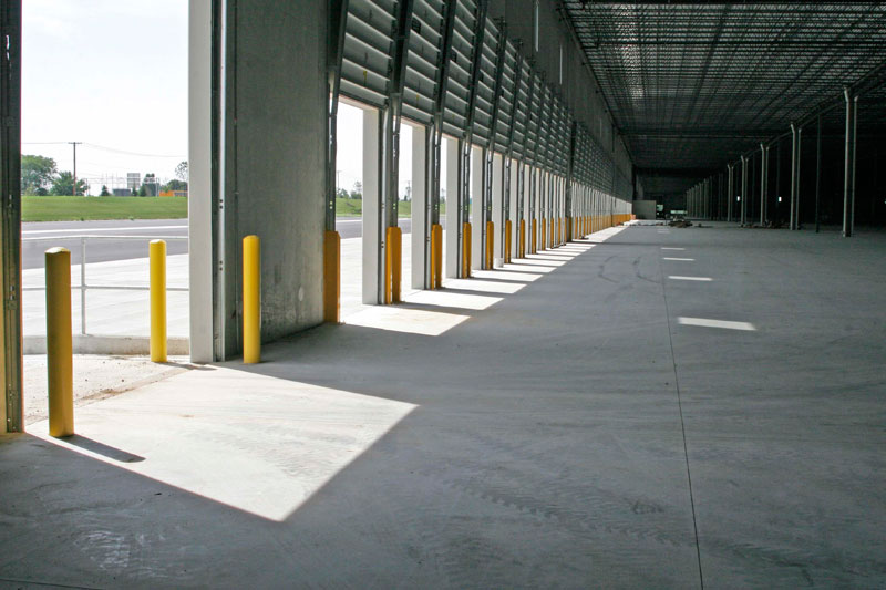 Light and shadow play on the concrete floor of the Heartland Corporate Center from open bay doors in the shipping and deliverables area.