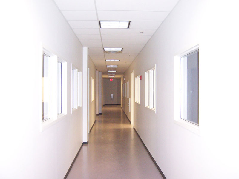 This image is of an interior hallway nestled between white walls with windows into the walkway of the newly renovated SGS Life Science facility done by Keeley Construction.