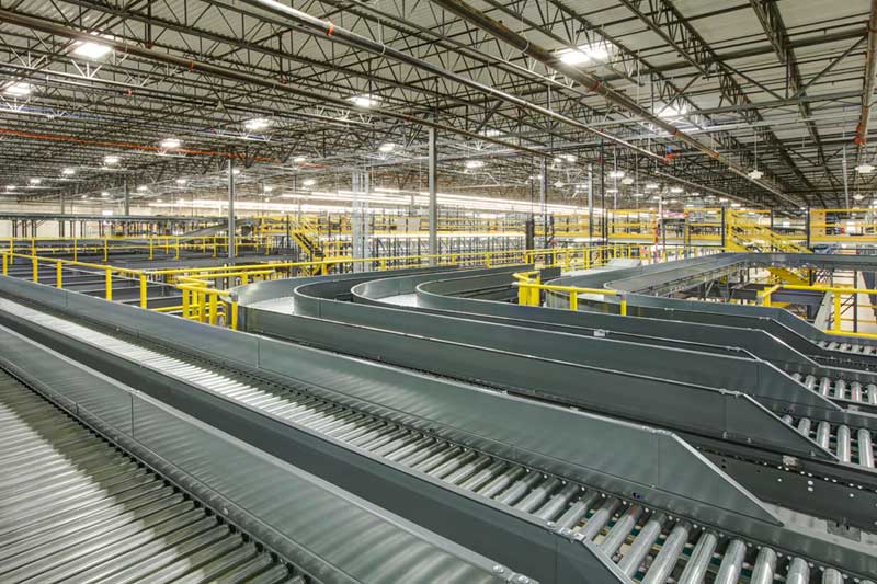 A brand-new room full of industrial racking and a large conveyor system inside the Wilton Industries warehouse.