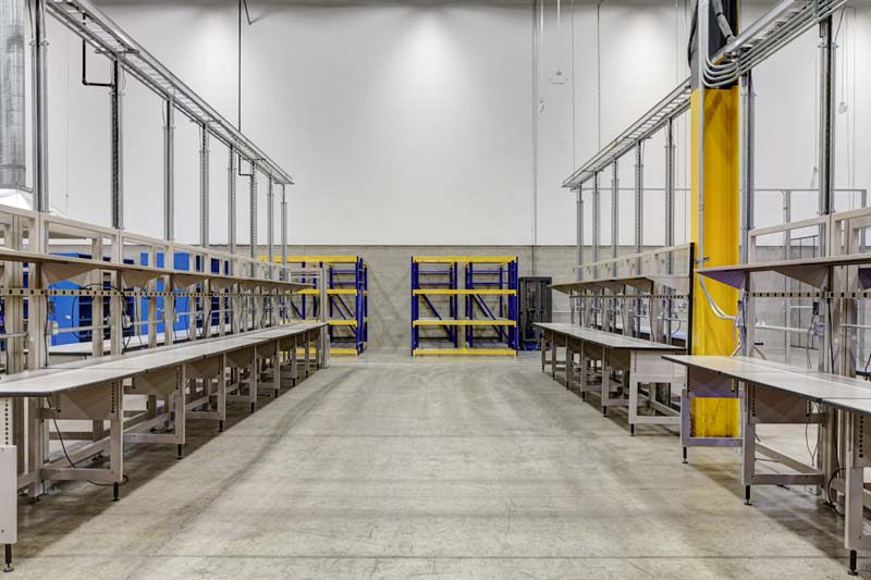 A look down the aisle of Zones’ giant industrial room flanked by empty benches and shelves.