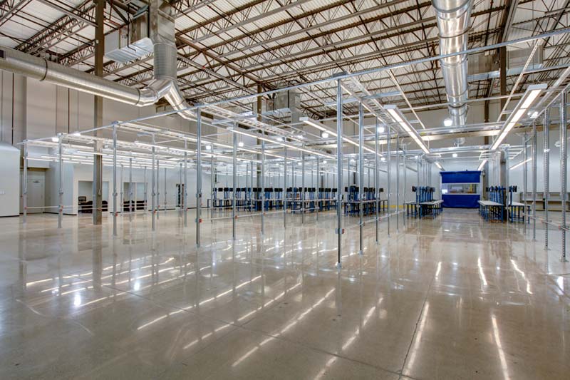 A large empty warehouse with metal grids and workstations in the back. Keeley Construction did the renovations to Zones’ facility.