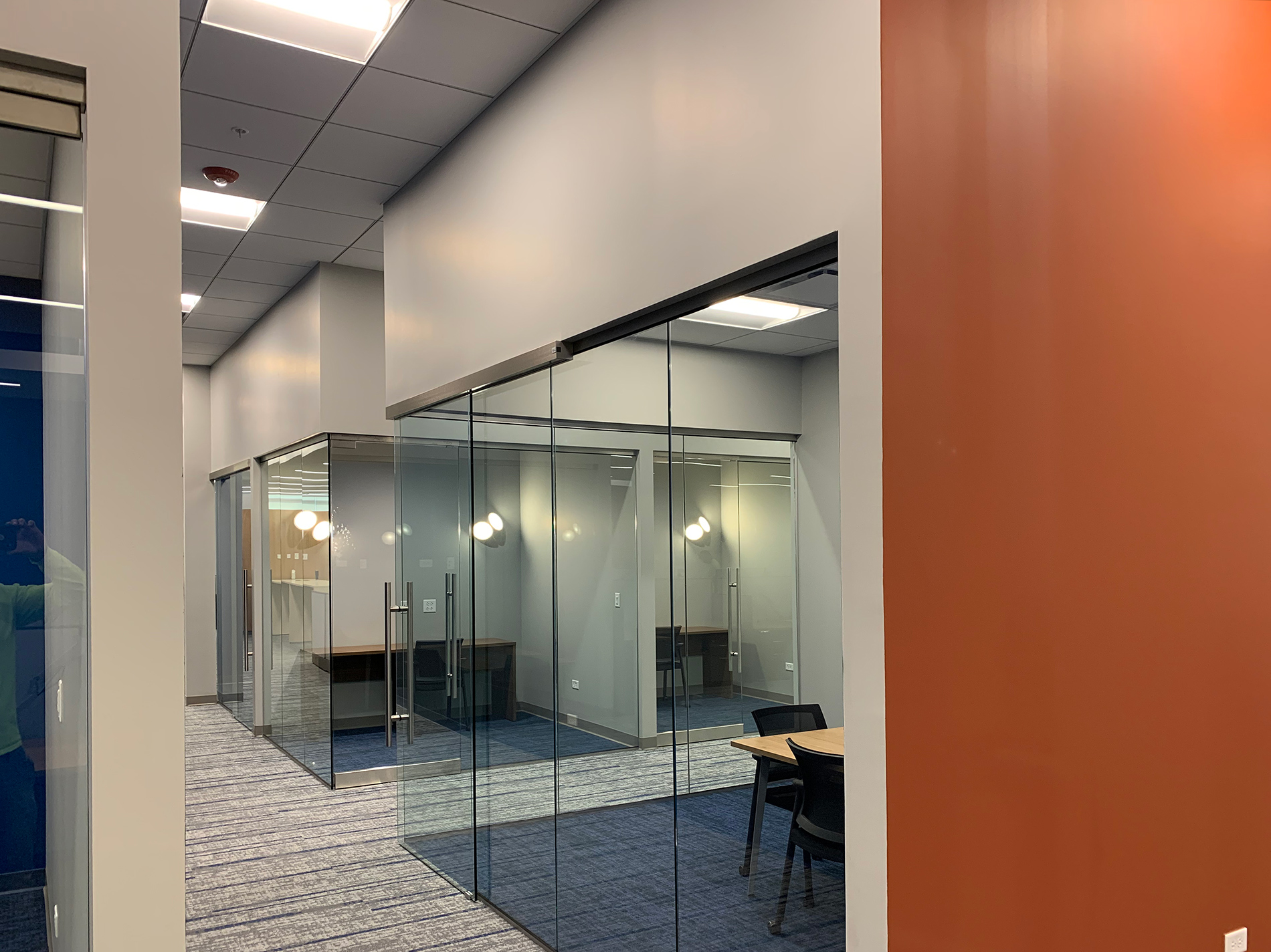 A hallway with walls of glass that separate office spaces. The CODA renovation project was completed by Keeley Construction, Inc.