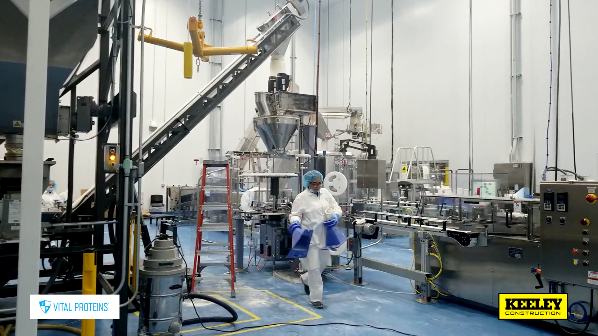 An employee in a white safety suit walks through the machinery in a production plant.