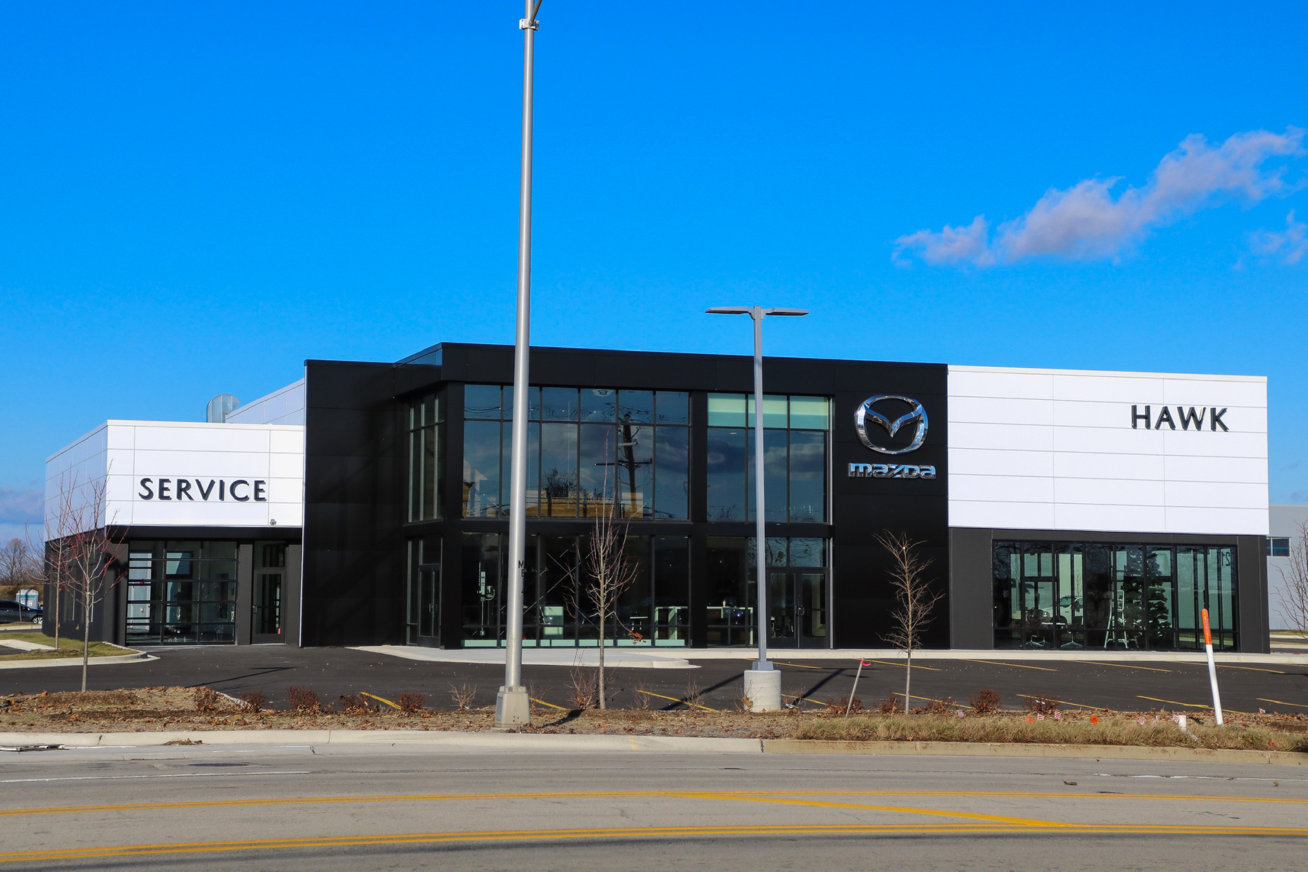 This is a view of the new Hawk Autos dealership showroom and service center. The front of the building has glass walls and two stories.