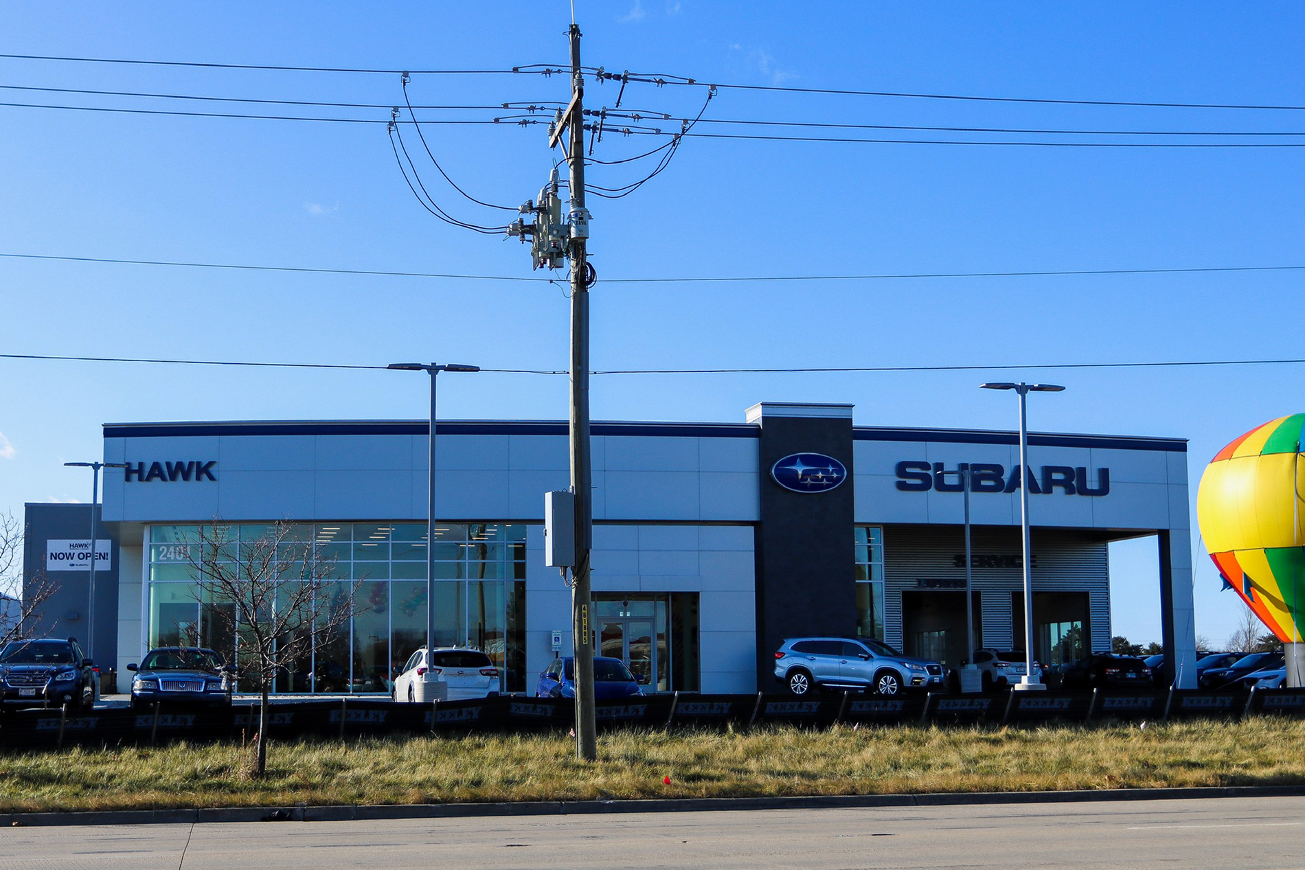 A side view of the new Hawk Auto dealership shows a large sign that says “Subaru” and “Hawk” above glass walls.