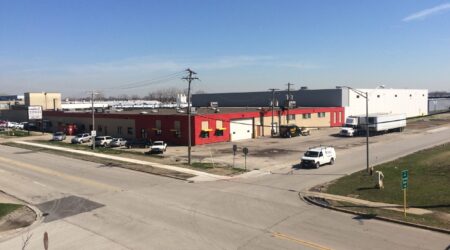 The finished red and white Pure’s Food building, completed by Keeley Construction, Inc., sits on the corner of a block. A couple of cars and a truck are occupying the streets surrounding the facility.