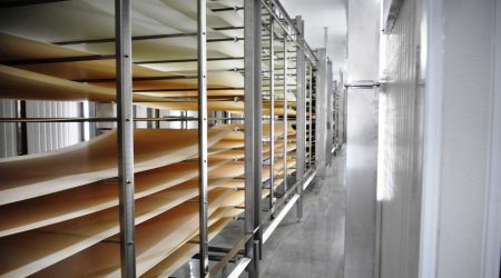 A clean, long stainless steel rack extends down the length of the interior of Grecian’s Delight cold storage and food processing facility.