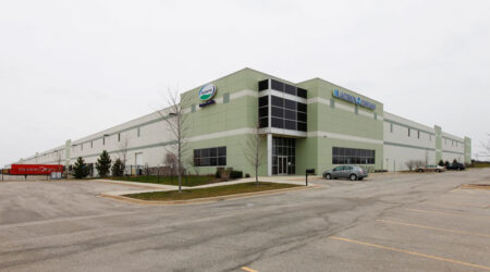 The large exterior of the Jacobson Companies’ food-grade warehouse and office facility sits against a grey sky on an empty parking lot.