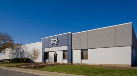 The O’Hare Industrial Park Façade Renovation, completed by Keeley Construction, included this office and warehouse facility, which sits under a bright, cloudless blue sky. Green spaces outline the entrance, and the sign on the blue building top reads, “Popcorn Palace.”